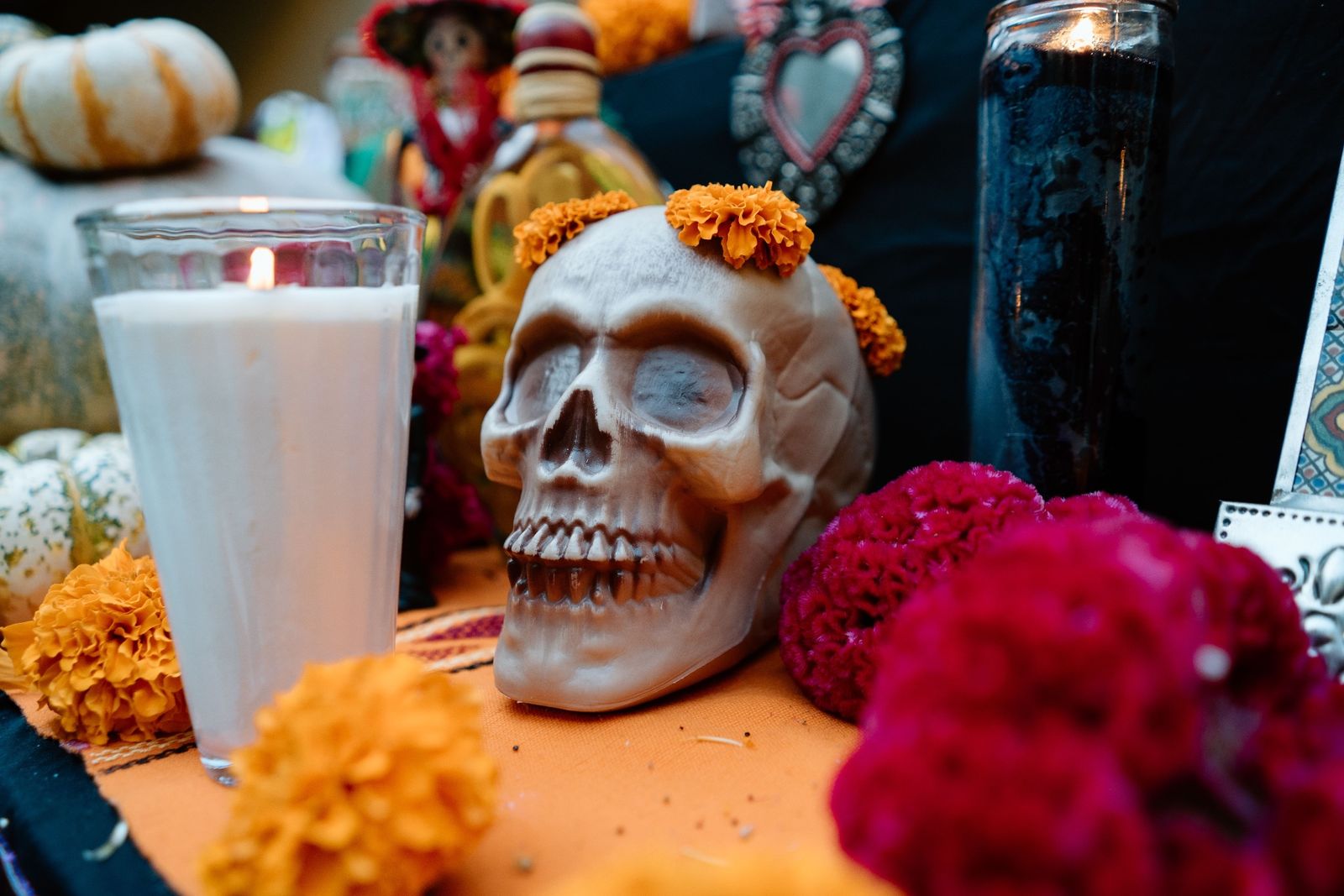 La fête des Morts sur la Riviera Maya : traditions et découvertes entre octobre et novembre Autel de la fête des Morts avec un crâne décoratif orné de fleurs de cempasúchil, des bougies allumées et des fleurs rouges